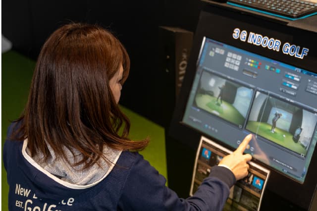 シミュレーションゴルフのスイング分析画面を女性が見ている様子